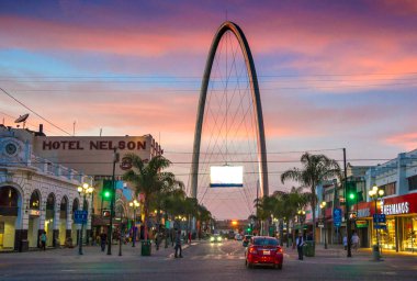 Mexico - Tijuana - Avenida Revolucion (Revolution street), the main touristic artery in Tijuana, with the millennial arch (el arco y reloj monumental) in a perpective at dusk clipart
