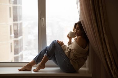 Genç kadın kahve içme pencereden