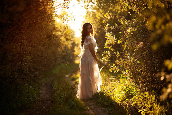 Beautiful young woman in a dress at sunset