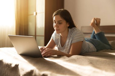 Kız kot pantolon bir dizüstü bilgisayar önünde yatıyor