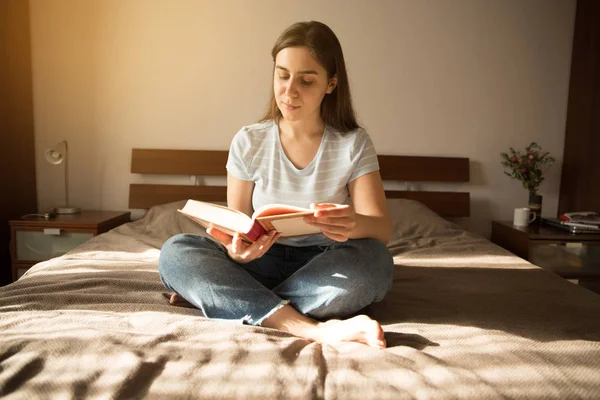 Mädchen Sitzt Auf Einem Bett Und Liest Ein Buch — Stockfoto
