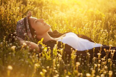 Şapkalı Kız kır çiçekleri arasında yalan ve bir şey hakkında hayal mutlu