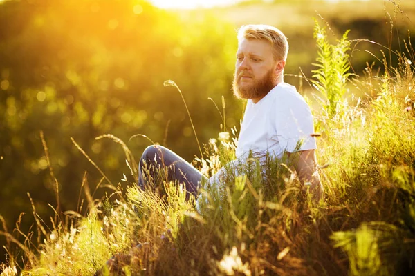 Glücklicher bärtiger Kerl, der inmitten von Wildblumen ruht — Stockfoto