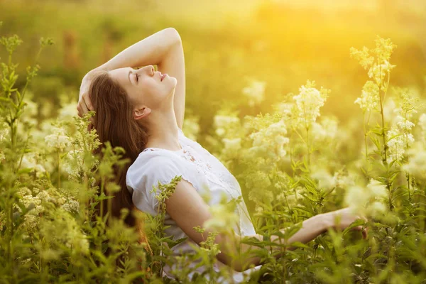 Gelukkig mooi meisje staat onder wilde bloemen — Stockfoto