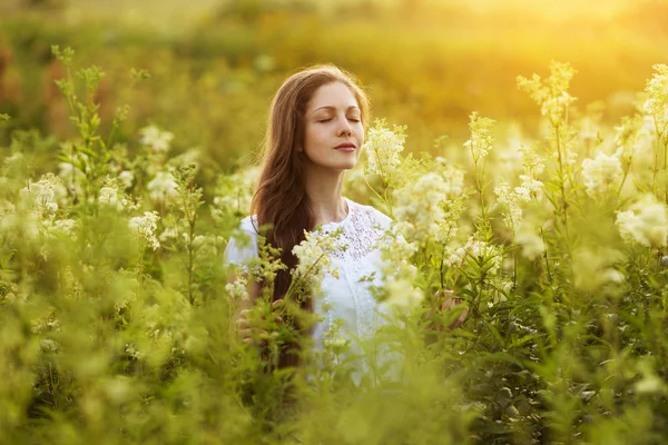 Glad vacker flicka står bland blommor — Stockfoto