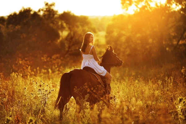 Девушка в белом платье верхом на лошади — стоковое фото