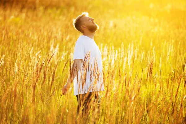 Szczęśliwy młody człowiek stoi w polu — Zdjęcie stockowe