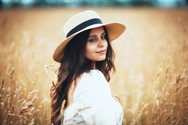 Belle femme en chapeau de paille parmi l'herbe des champs — Photo