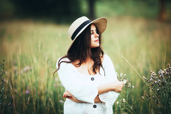 Piękna kobieta w słomkowym kapeluszu wśród trawy pola — Zdjęcie stockowe