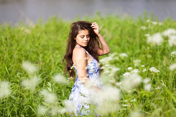 Vacker kvinna i blå klänning bland vildblommor — Stockfoto