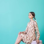Menina jovem atraente sentado em grande macaron, em turquesa
