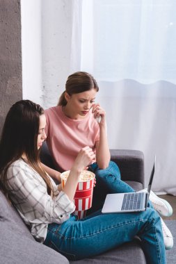 patlamış mısır yemek ve dizüstü çök evde tutan kız arkadaşı ile genç kadın film seyrederken ağlıyor