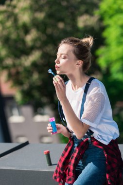 attractive young woman using bubble blower at rooftop  clipart