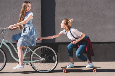 gülümseyen bisiklet sürme ve onun kız arkadaşı kaykay üzerinde çekme kadın 