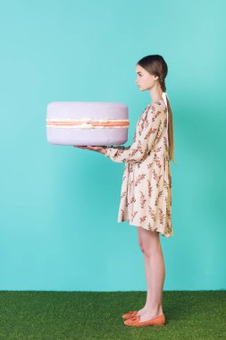 büyük mor macaron, Turkuaz üzerinde tutan şık genç kız