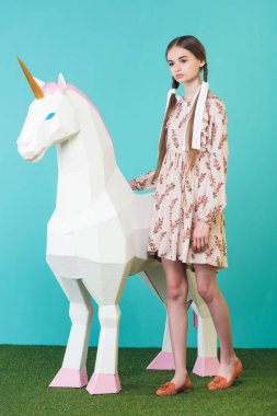 Turkuaz üzerinde büyük beyaz unicorn ile güzel şık genç kız