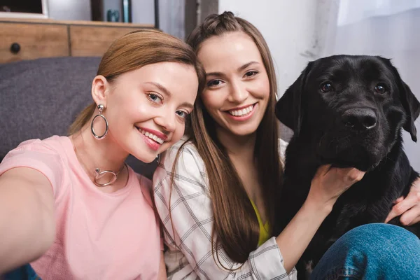 Joven Sonriente Mujer Tomando Selfie Con Amiga Labrador Negro Casa — Foto de Stock