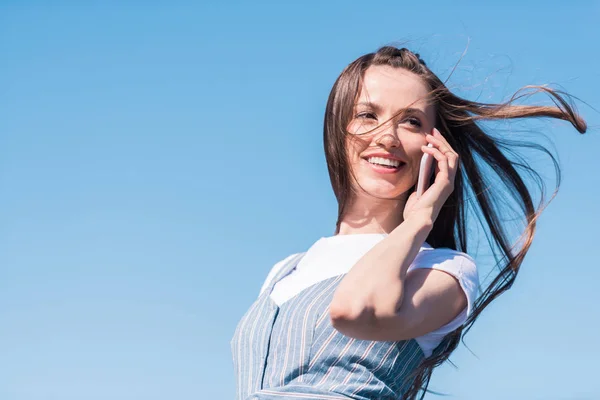 Sonriente Mujer Joven Atractiva Hablando Teléfono Inteligente Contra Cielo Azul — Foto de Stock