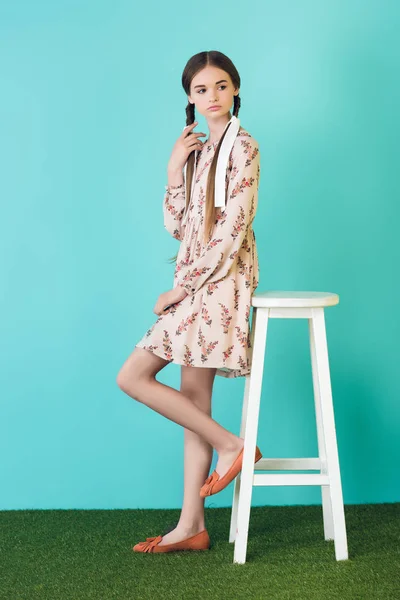 少女在时髦的夏天礼服与辫子摆在凳子附近 在绿松石 — 图库照片