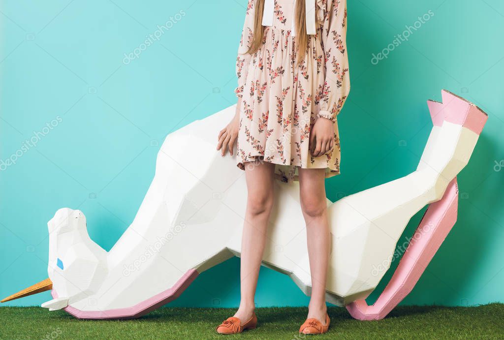 cropped view of model posing with big unicorn upside down, on blue