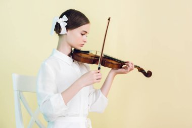 güzel genç müzisyen beyaz kıyafeti keman, sarı izole çalmaya