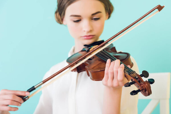 beautiful girl playing violin, isolated on blue