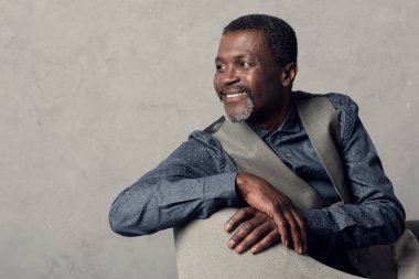 koltukta oturan yelek neşeli olgun Afrikalı-Amerikalı adam portresi
