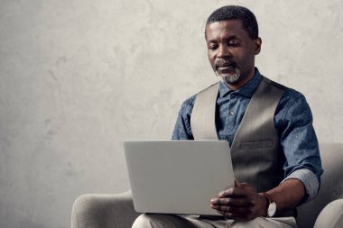 koltukta oturan dizüstü bilgisayar ile kendine güvenen Afrikalı-Amerikalı işadamı 
