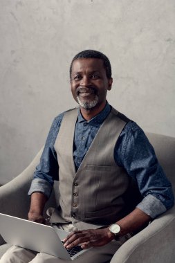 koltuk dizüstü bilgisayar ile oturup mutlu Afrika kökenli Amerikalı iş adamı 