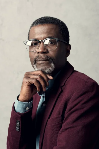 stock image portrait of pensive african american man in trendy eyeglasses and burgundy jacket