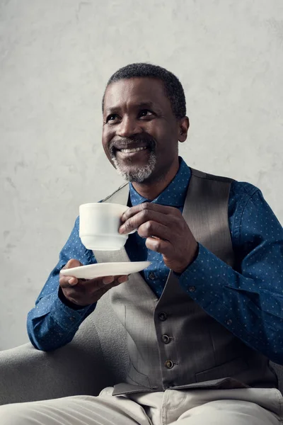 Glücklich Stilvollen Afrikanisch Amerikanischen Mann Mit Tasse Kaffee Sitzen Sessel — kostenloses Stockfoto