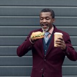 Stylish african american man with disposable cup of coffee and yummy hamburger