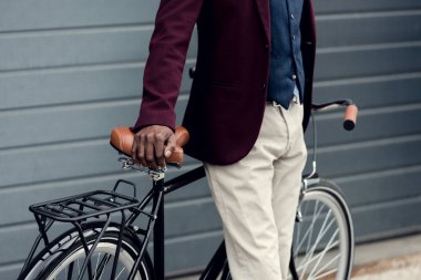 şık Afrikalı-Amerikalı adam bisikletin üstünde eğilerek görünümünü kırpılmış 