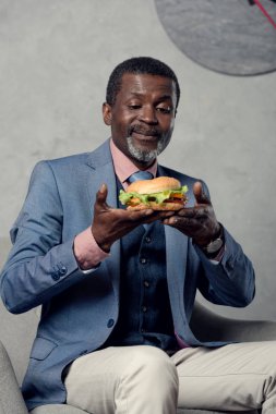 mutlu orta yaşlı Afrikalı-Amerikalı işadamı hamburger ile