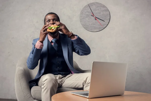 Hombre Afroamericano Maduro Comiendo Hamburguesa Mesa Con Ordenador Portátil — Foto de Stock