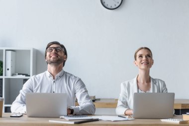 dizüstü bilgisayarlar ile birlikte çalışan ve ofiste bakarken mutlu genç yöneticileri
