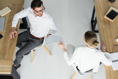 overhead view of businesspeople passing papers on workplace at office clipart