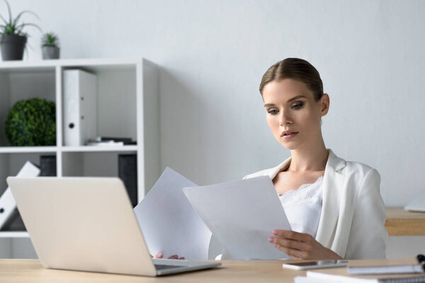 focused young businesswoman doing paperwork at office