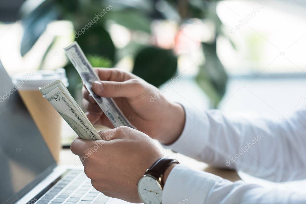 cropped shot of businessman counting cash at office