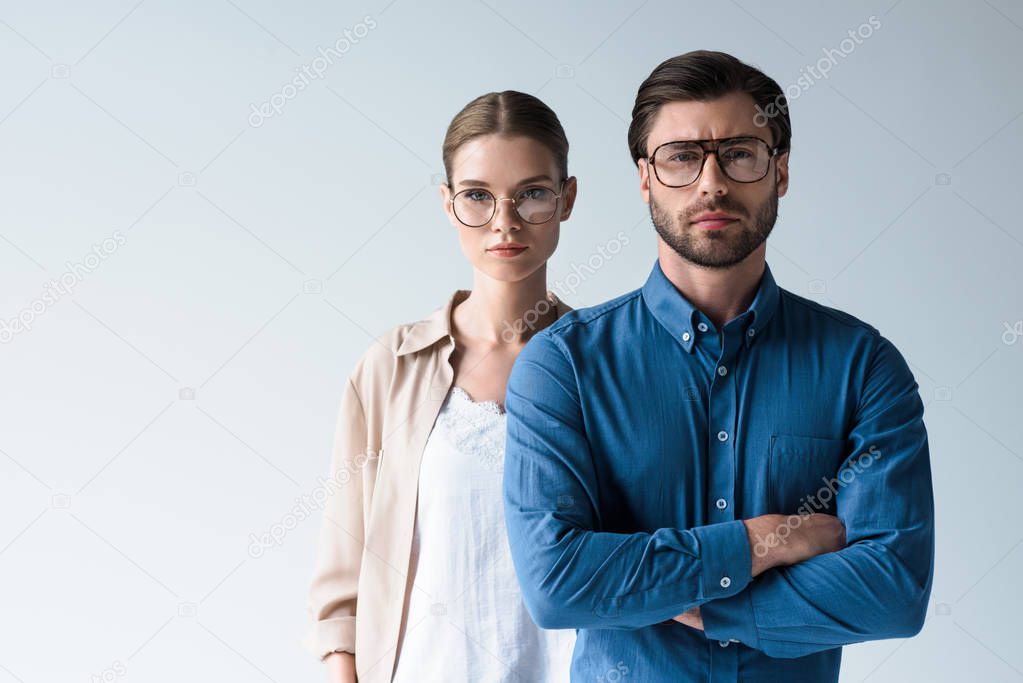 serious man and woman in stylish clothing and eyeglasses isolated on white