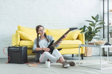 kadın genç müzisyen katta oturma odasında elektro gitar çalmak