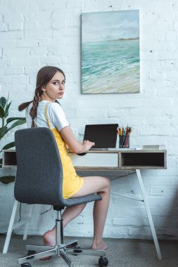 dizüstü bilgisayar kullanarak ve oda masada oturan çekici genç kız 