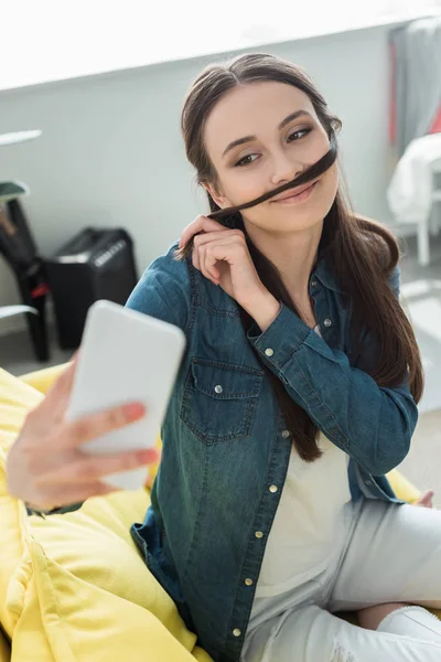 Sorrindo Adolescente Fazendo Falso Bigode Cabelo Enquanto Toma Selfie Com — Fotografia de Stock Grátis