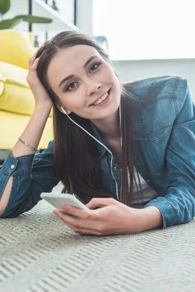 Όμορφη Νεαρή Γυναίκα Στα Ακουστικά Χρησιμοποιώντας Smartphone Και Χαμογελαστός Στην — Φωτογραφία Αρχείου