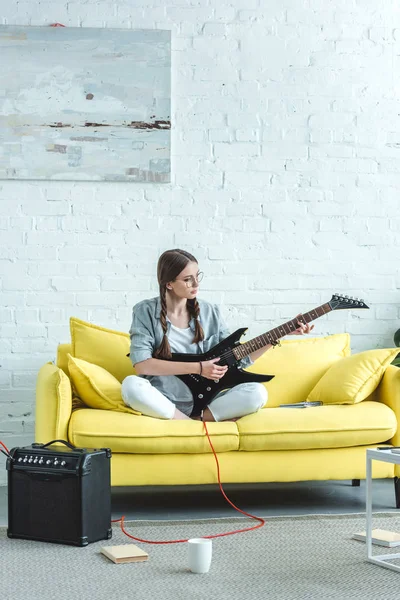 美丽的少女在客厅沙发上玩电吉他 — 图库照片