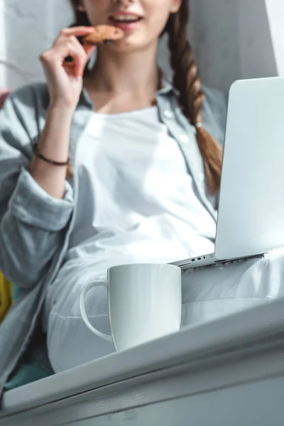 Vista Cortada Menina Usando Laptop Comer Biscoito Com Chá — Fotografia de Stock Grátis