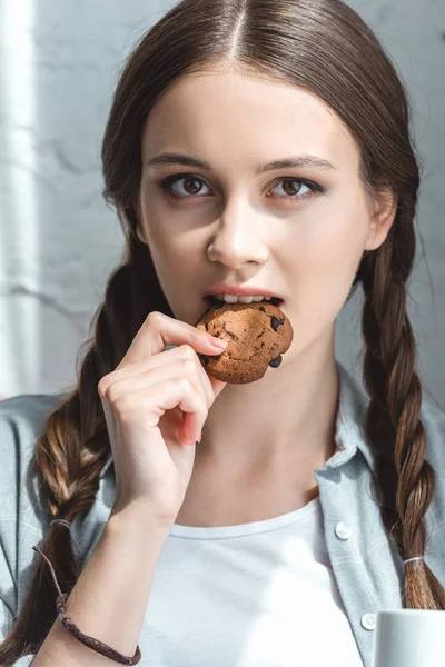 Krásné Dospívající Dívka Jíst Cookie Při Pohledu Fotoaparát — Stock fotografie