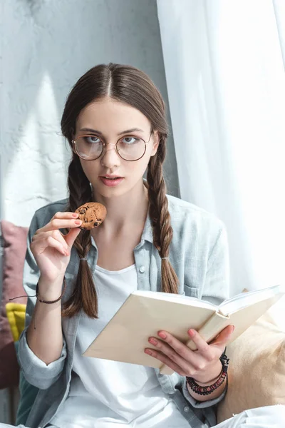 Gadis Cantik Berkacamata Membaca Buku Dan Makan Kue — Foto Stok Gratis