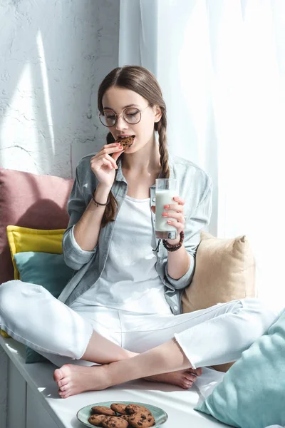 Mooie Tiener Meisje Met Glas Melk Eten Cookie Vensterbank — Stockfoto