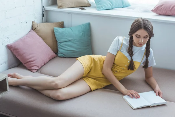 Schöne Teen Mädchen Mit Zöpfen Lesen Buch Auf Dem Sofa — Stockfoto